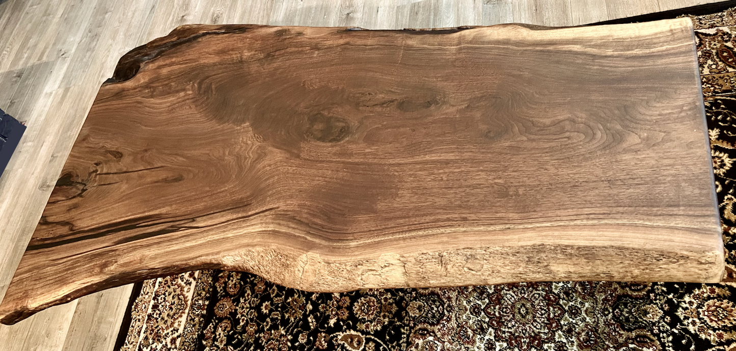 Top-down view of large live edge black walnut coffee table, highlighting natural wood grain, and live edge details. Handcrafted live edge walnut coffee table styled in a modern living room with a cozy, rustic aesthetic. Detailed view of live edge walnut wood grain, showing natural color variations, and organic patterns. Large live edge black walnut coffee table made from walnut featuring unique grain patterns and a smooth, polished surface. Rustic and modern design.