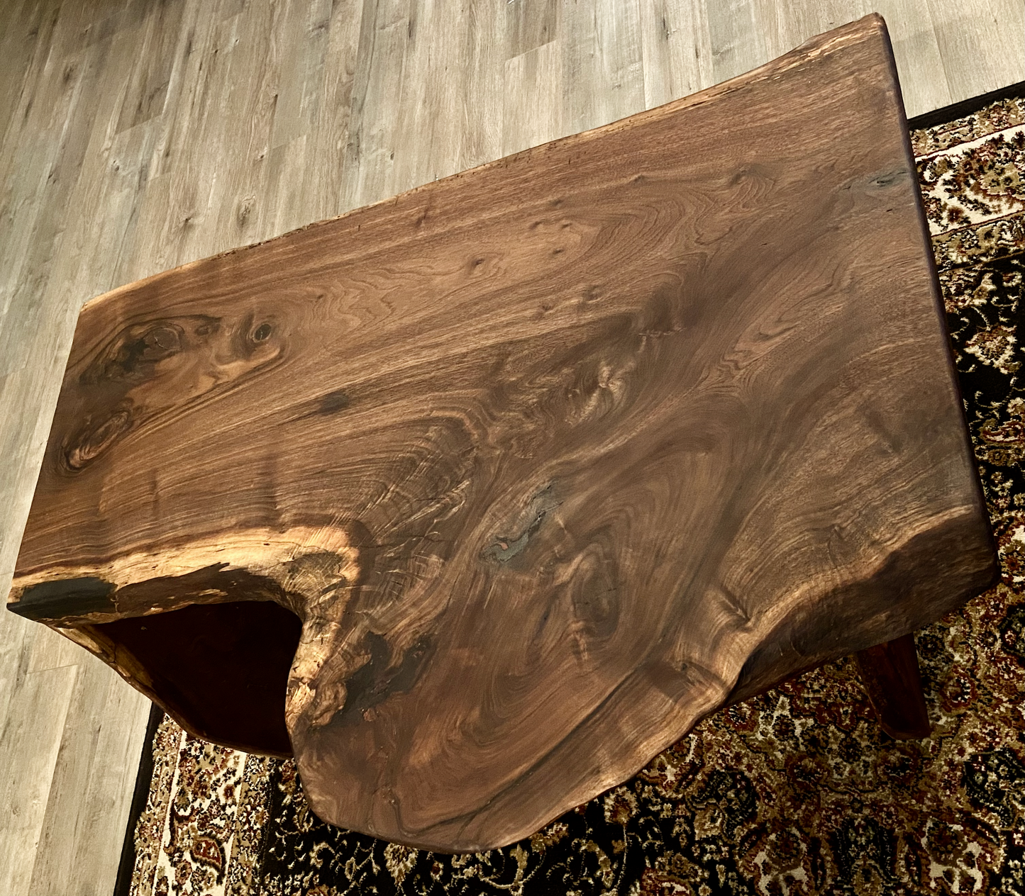 Top-down view of live edge black walnut waterfall wood coffee table highlighting natural wood grain, and live edge details. Handcrafted live edge walnut coffee table styled in a modern living room with a cozy, rustic aesthetic. Detailed view of walnut wood grain, showing natural color variations, and organic patterns. Live edge waterfall coffee table made from black walnut, featuring unique grain patterns and a smooth, polished surface. Rustic and modern design.