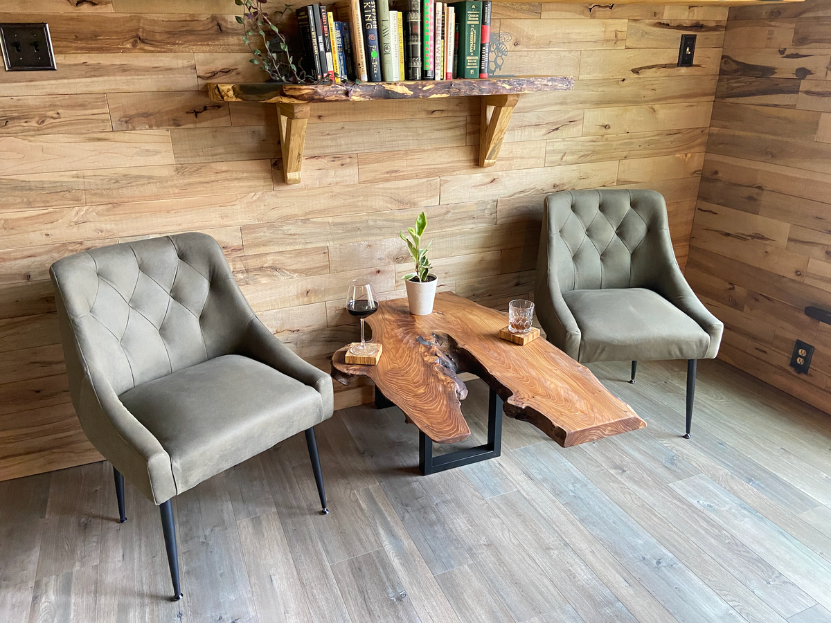 Modern interior with two gray chairs and a wooden chestnut coffee table against a wooden wall that has a live edge maple shelf.