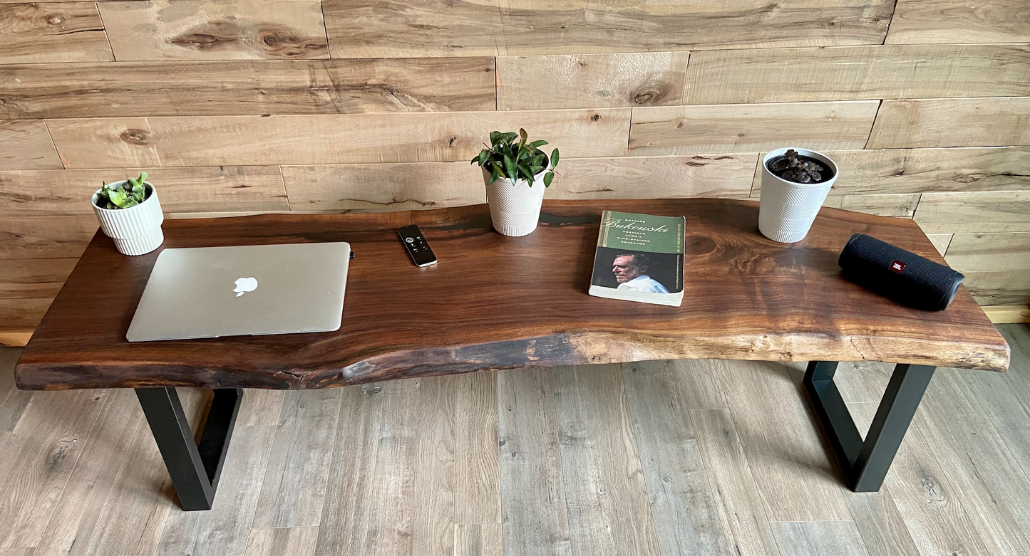 Live edge walnut bench with steel legs against a wood-paneled wall on wood flooring. Live edge walnut coffee table styled with everyday items, showcasing its versatility and natural wood grain.