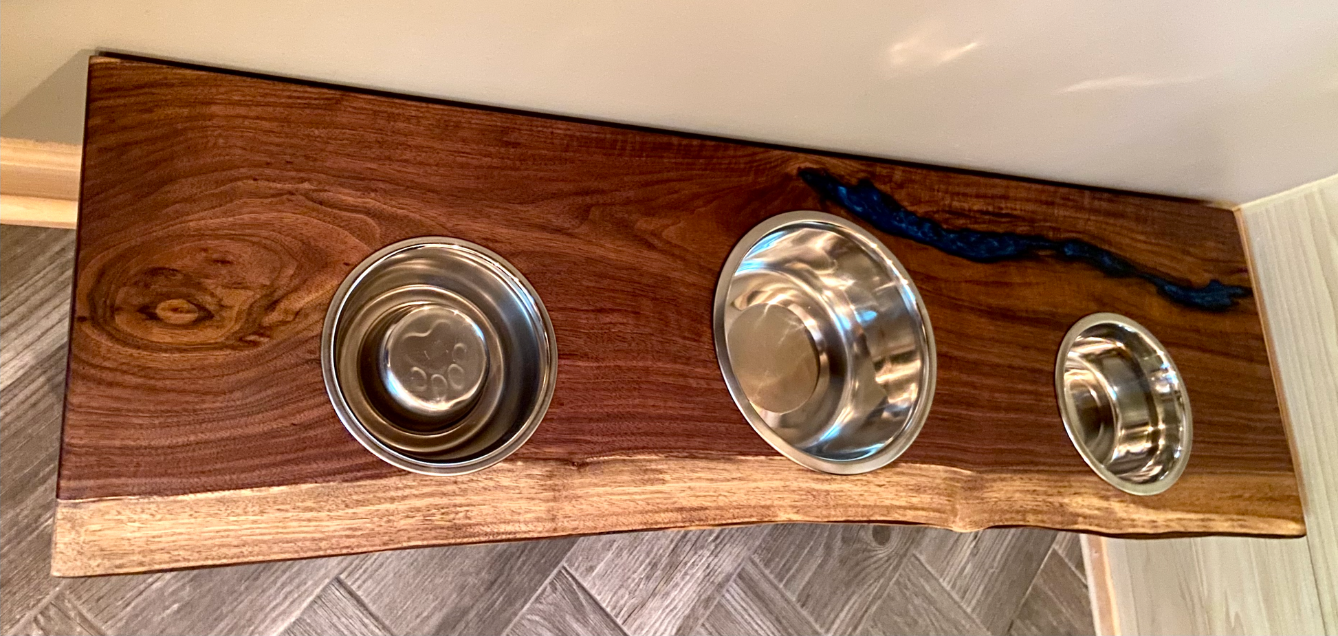 Live edge raised pet stand crafted from spalted maple or black walnut, featuring two stainless steel bowls for food and water. Elevated pet feeder, showcasing the natural wood grain and sturdy construction. Top-down view highlighting the placement of the three stainless steel bowls within the live edge wooden stand. Detailed close-up of the spalted maple’s unique wood grain patterns on the pet stand.