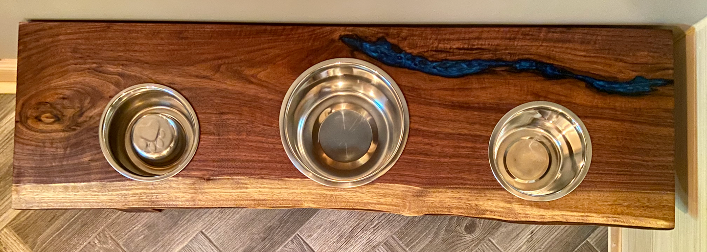 Live edge raised pet stand crafted from spalted maple or black walnut, featuring two stainless steel bowls for food and water. Elevated pet feeder, showcasing the natural wood grain and sturdy construction. Top-down view highlighting the placement of the three stainless steel bowls within the live edge wooden stand. Detailed close-up of the spalted maple’s unique wood grain patterns on the pet stand.
