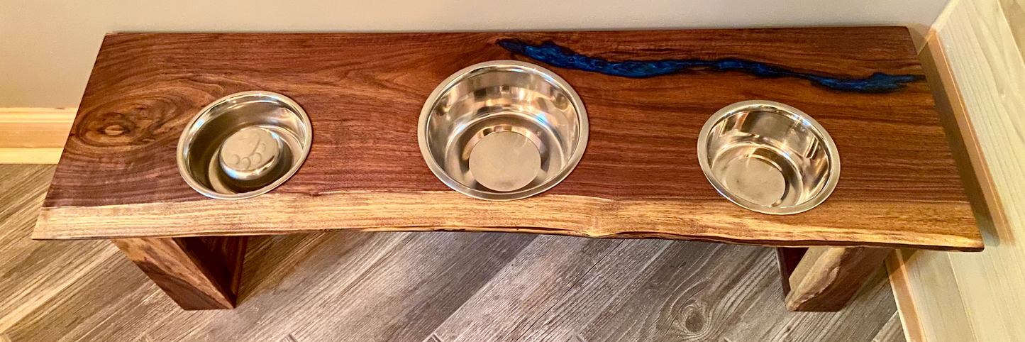 Live edge raised pet stand crafted from spalted maple or black walnut, featuring two stainless steel bowls for food and water. Elevated pet feeder, showcasing the natural wood grain and sturdy construction. Top-down view highlighting the placement of the three stainless steel bowls within the live edge wooden stand. Detailed close-up of the spalted maple’s unique wood grain patterns on the pet stand.
