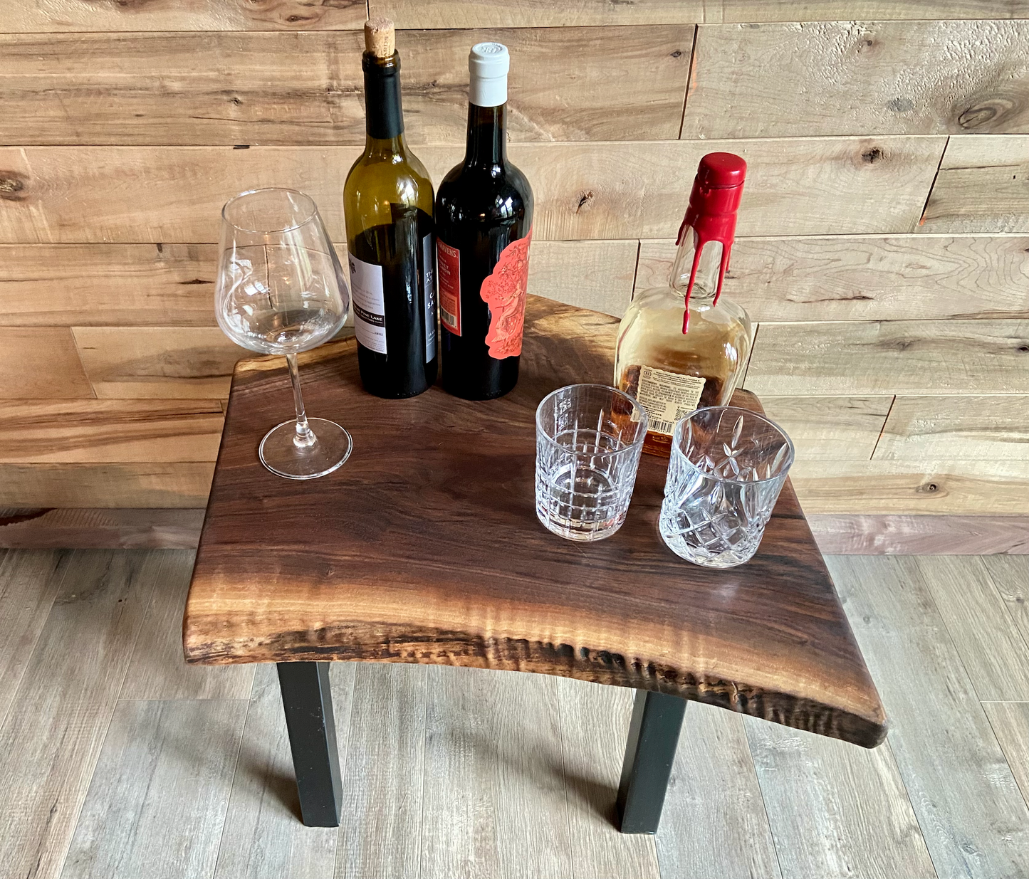 Top-down view of a live edge walnut side table with rich natural grain and smooth finish, set against a maple wall. Live edge walnut side table styled with everyday items, showing rustic charm and organic wood edge.