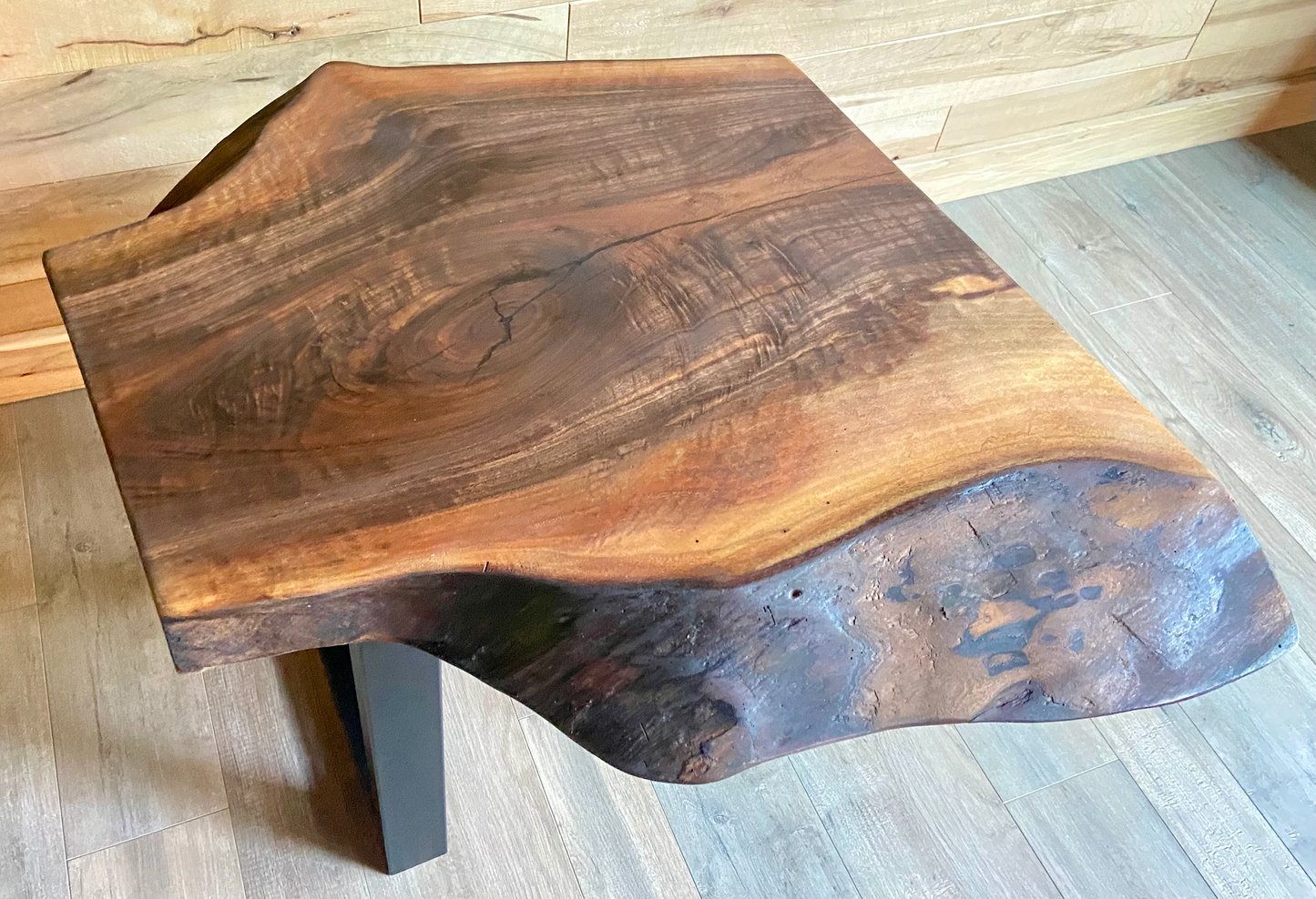Wooden coffee table with a natural, wavy edge design on a wooden floor.