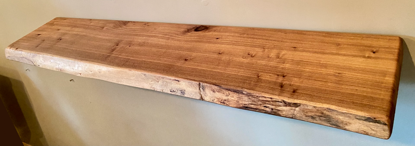 Close-up side view of a rustic live edge wood floating shelf showing natural grain and curvature.