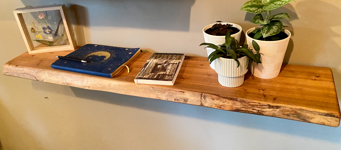 Close-up side view of a rustic live edge wood floating shelf showing natural grain and curvature.