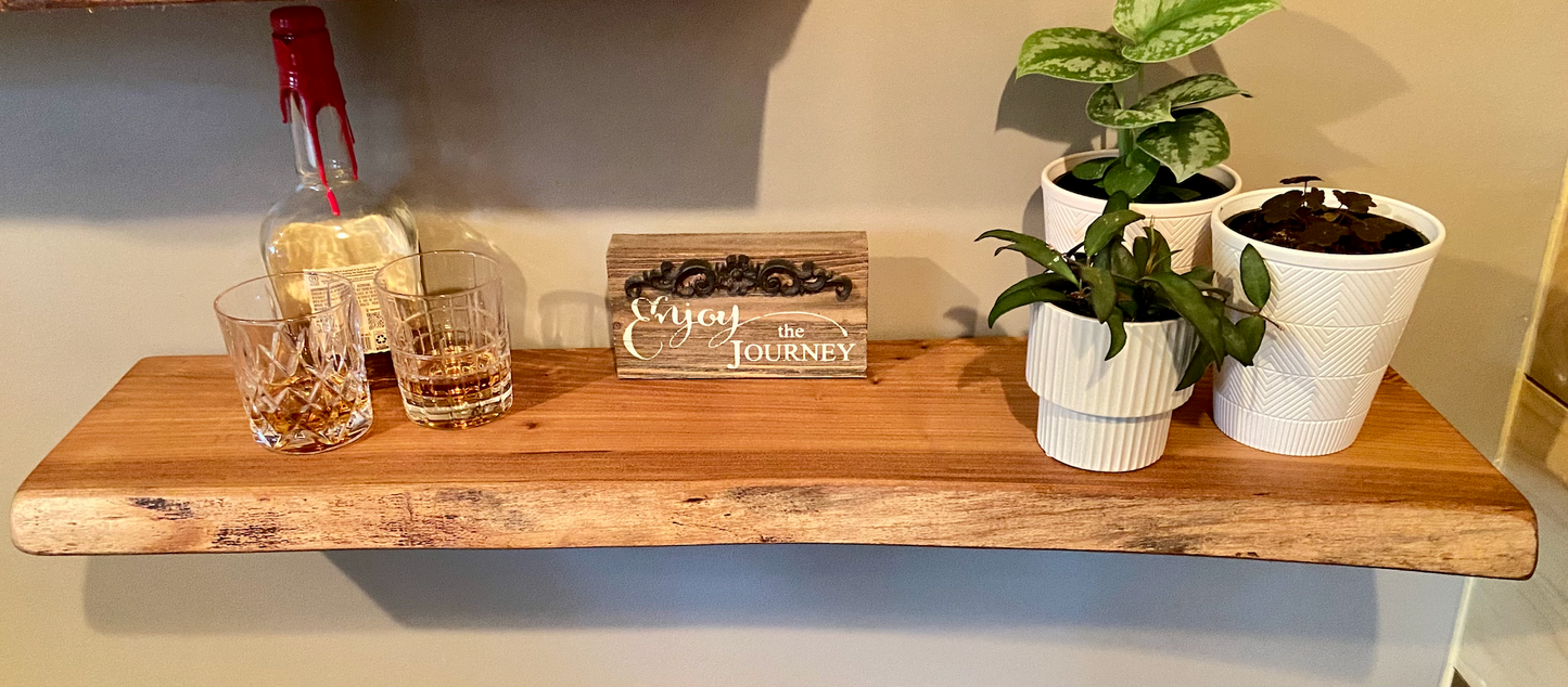 Close-up side view of a rustic live edge wood floating shelf showing natural grain and curvature.