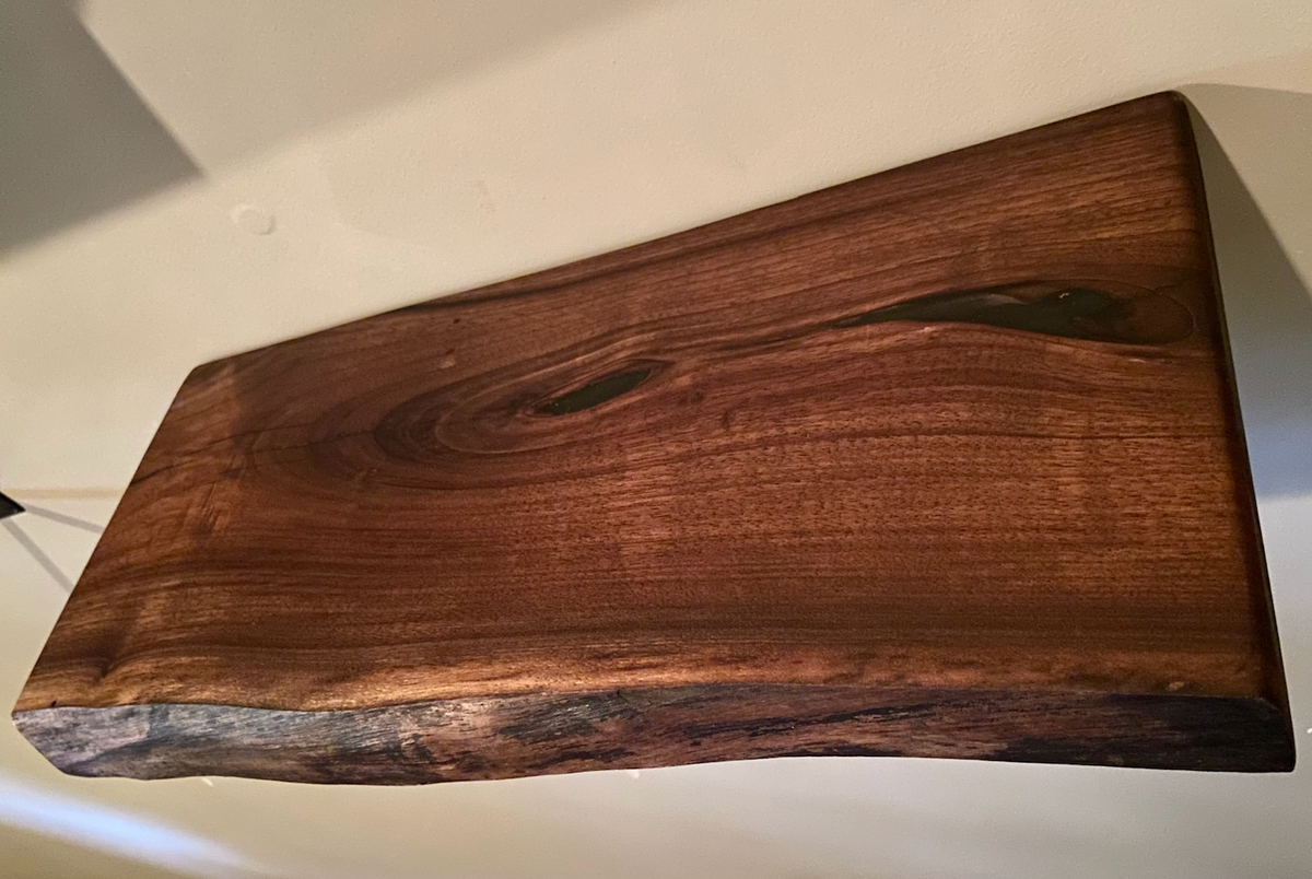 Custom live edge walnut shelves featuring rich, dark brown wood grain and organic edges. Handcrafted for stylish, rustic home decor.