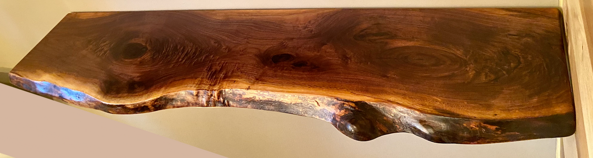 Custom live edge walnut shelves featuring rich, dark brown wood grain and organic edges. Handcrafted for stylish, rustic home decor.
