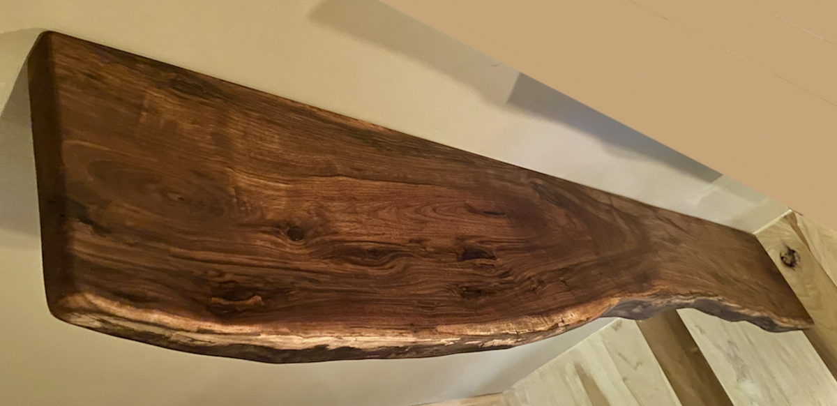 Custom live edge walnut shelves featuring rich, dark brown wood grain and organic edges. Handcrafted for stylish, rustic home decor.