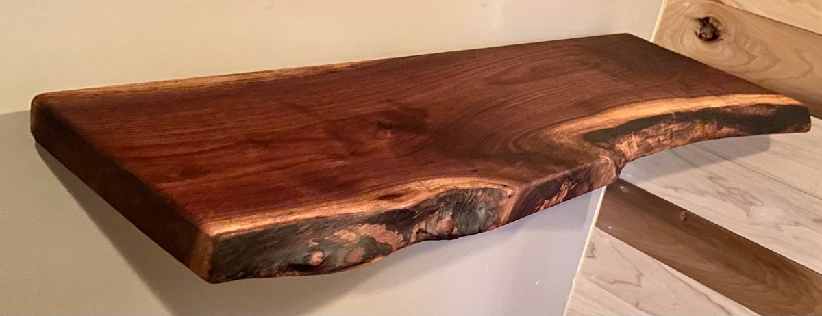 Custom live edge walnut shelves featuring rich, dark brown wood grain and organic edges. Handcrafted for stylish, rustic home decor.