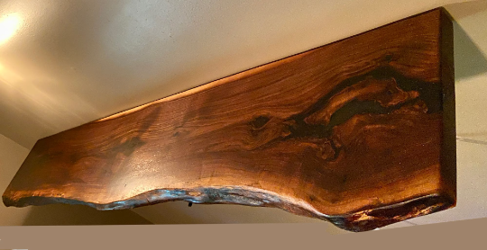 Custom live edge walnut shelves featuring rich, dark brown wood grain and organic edges. Handcrafted for stylish, rustic home decor.