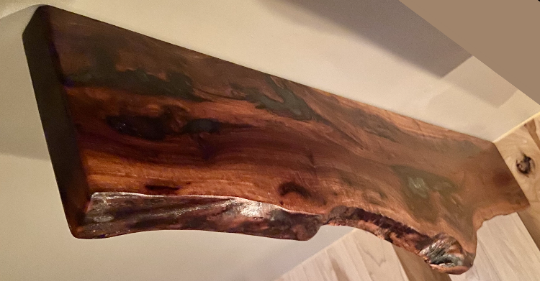 Custom live edge walnut shelves featuring rich, dark brown wood grain and organic edges. Handcrafted for stylish, rustic home decor.