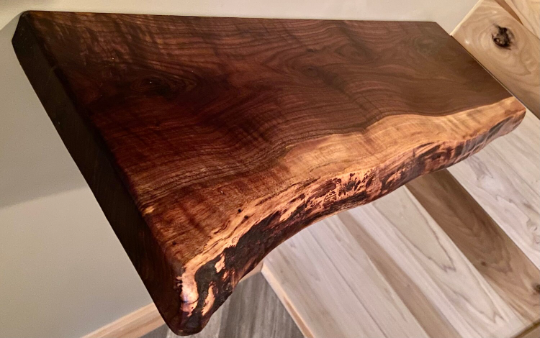 Custom live edge walnut shelves featuring rich, dark brown wood grain and organic edges. Handcrafted for stylish, rustic home decor.