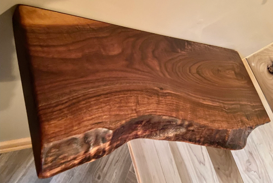 Custom live edge walnut shelves featuring rich, dark brown wood grain and organic edges. Handcrafted for stylish, rustic home decor.