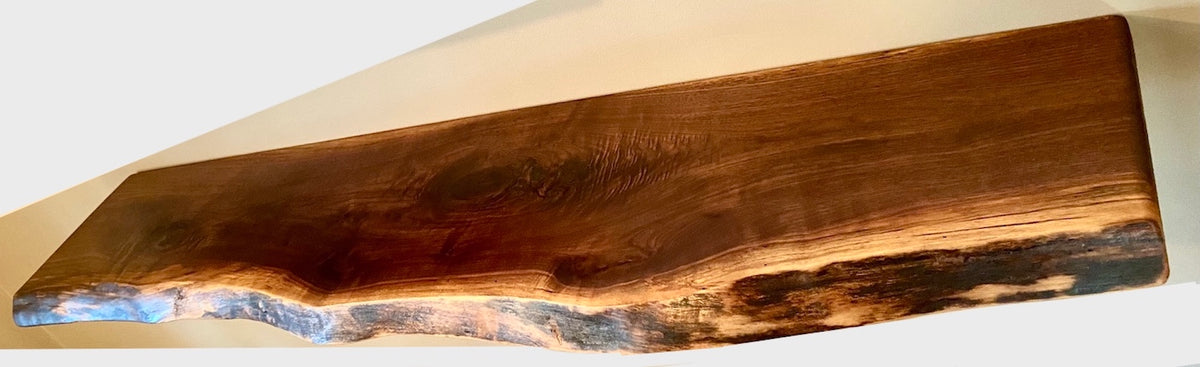 Custom live edge walnut shelves featuring rich, dark brown wood grain and organic edges. Handcrafted for stylish, rustic home decor.