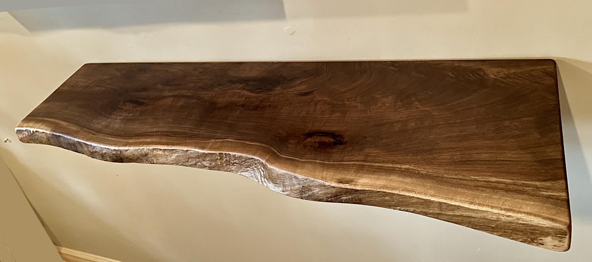 Custom live edge walnut shelves featuring rich, dark brown wood grain and organic edges. Handcrafted for stylish, rustic home decor.