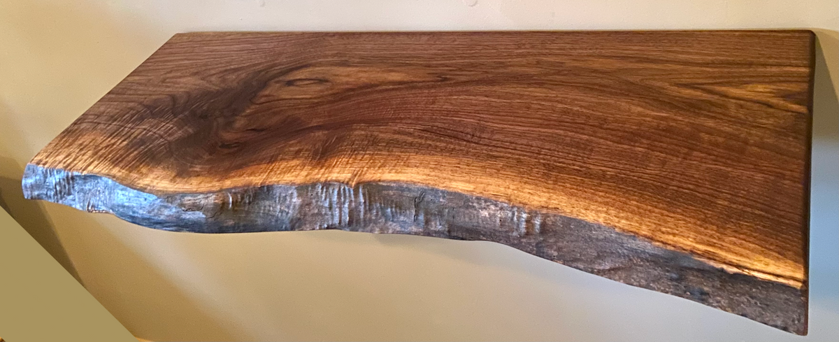 Custom live edge walnut shelves featuring rich, dark brown wood grain and organic edges. Handcrafted for stylish, rustic home decor.