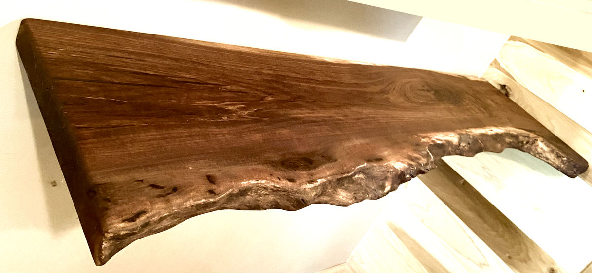 Custom live edge walnut shelves featuring rich, dark brown wood grain and organic edges. Handcrafted for stylish, rustic home decor.