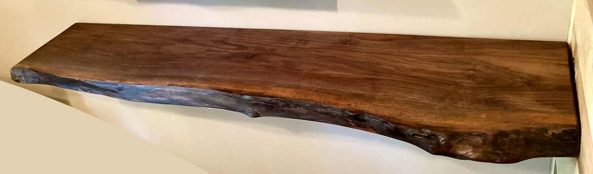 Custom live edge walnut shelves featuring rich, dark brown wood grain and organic edges. Handcrafted for stylish, rustic home decor.
