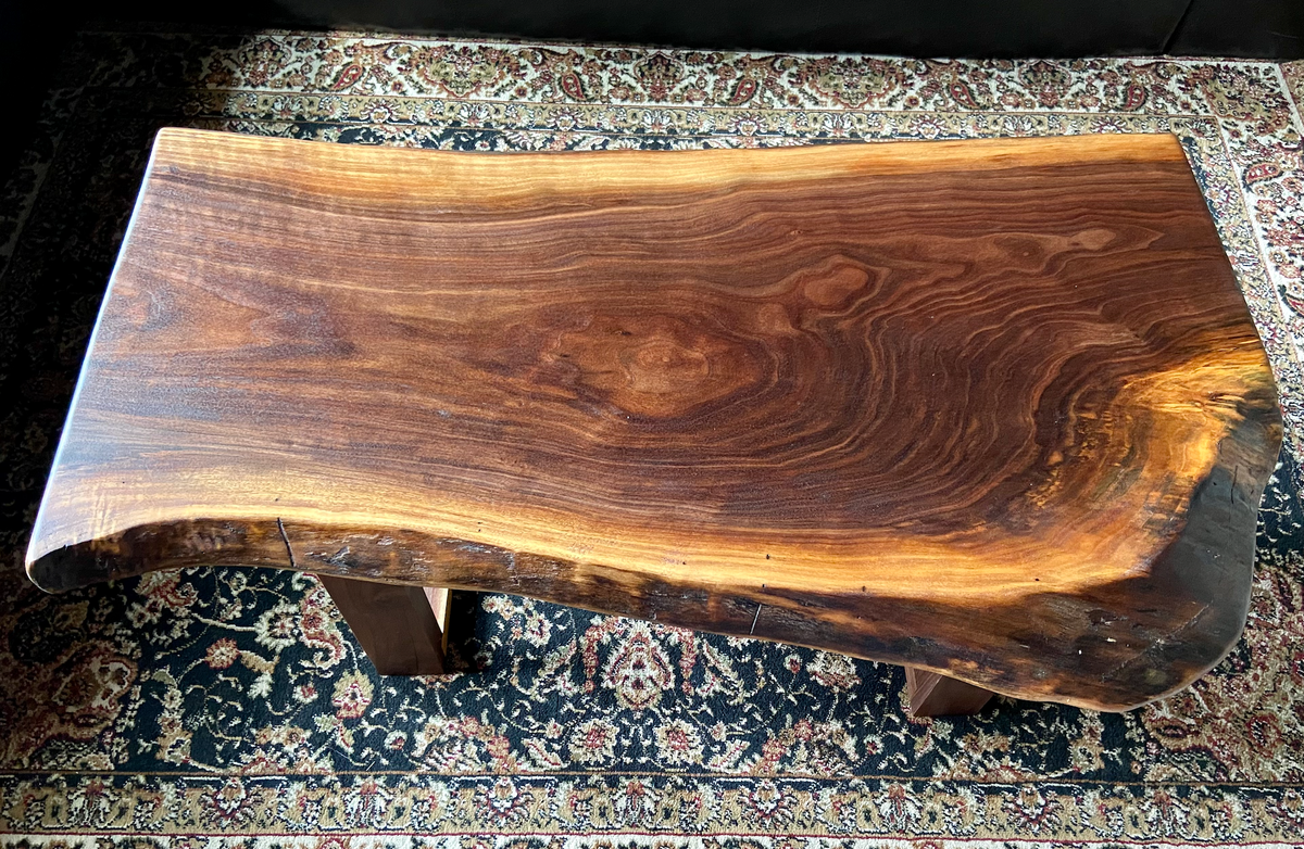 Live edge walnut wood slab coffee table with a natural finish on a patterned rug