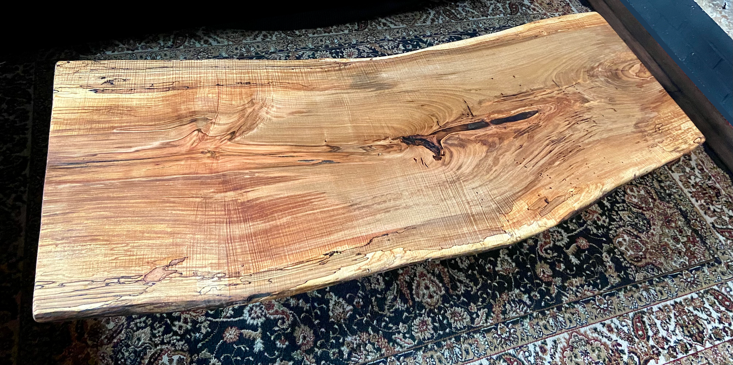 Top-down view of live edge ambrosia maple coffee table, highlighting natural wood grain, warm tones, and live edge details. Handcrafted ambrosia maple coffee table styled in a modern living room with a cozy, rustic aesthetic. Detailed view of ambrosia maple wood grain, showing natural spalting, color variations, and organic patterns. Curved live edge coffee table made from ambrosia maple, featuring unique grain patterns and a smooth, polished surface. Rustic and modern design.
