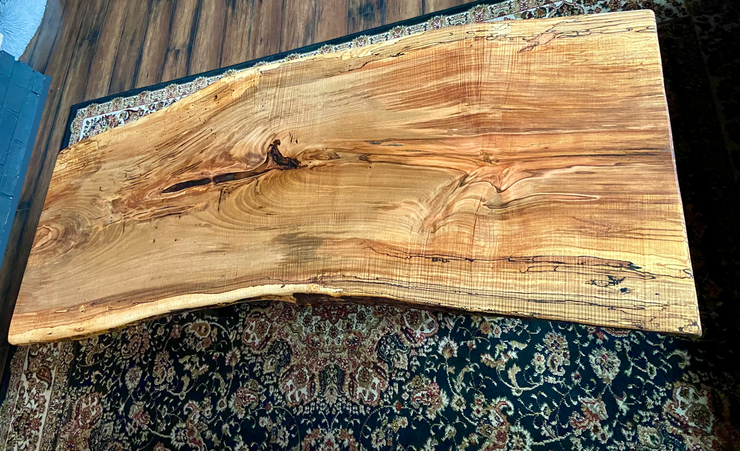 Top-down view of live edge ambrosia maple coffee table, highlighting natural wood grain, warm tones, and live edge details. Handcrafted ambrosia maple coffee table styled in a modern living room with a cozy, rustic aesthetic. Detailed view of ambrosia maple wood grain, showing natural spalting, color variations, and organic patterns. Curved live edge coffee table made from ambrosia maple, featuring unique grain patterns and a smooth, polished surface. Rustic and modern design.