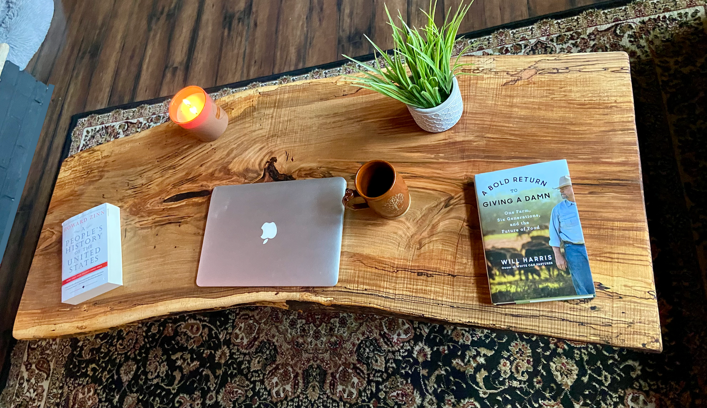 Top-down view of live edge ambrosia maple coffee table with household items, highlighting natural wood grain, and live edge details. Handcrafted ambrosia maple coffee table styled in a modern living room with a cozy, rustic aesthetic. Detailed view of ambrosia maple wood grain, showing natural spalting, color variations, and organic patterns. Curved live edge coffee table made from ambrosia maple, featuring unique grain patterns and a smooth, polished surface. Rustic and modern design.