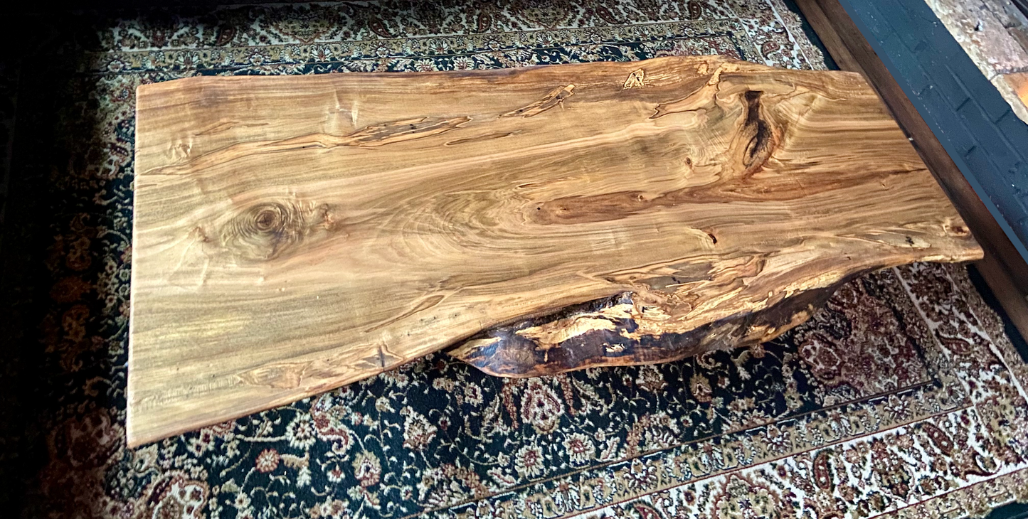 Top-down view of live edge ambrosia maple coffee table, highlighting natural wood grain, warm tones, and live edge details. Handcrafted ambrosia maple coffee table styled in a modern living room with a cozy, rustic aesthetic. Detailed view of ambrosia maple wood grain, showing natural spalting, color variations, and organic patterns. Curved live edge coffee table made from ambrosia maple, featuring unique grain patterns and a smooth, polished surface. Rustic and modern design.