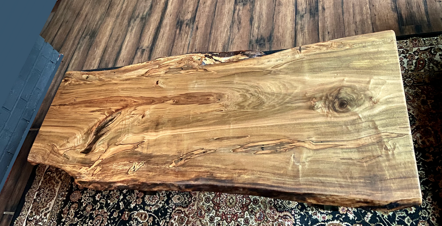 Top-down view of live edge ambrosia maple coffee table, highlighting natural wood grain, warm tones, and live edge details. Handcrafted ambrosia maple coffee table styled in a modern living room with a cozy, rustic aesthetic. Detailed view of ambrosia maple wood grain, showing natural spalting, color variations, and organic patterns. Curved live edge coffee table made from ambrosia maple, featuring unique grain patterns and a smooth, polished surface. Rustic and modern design.