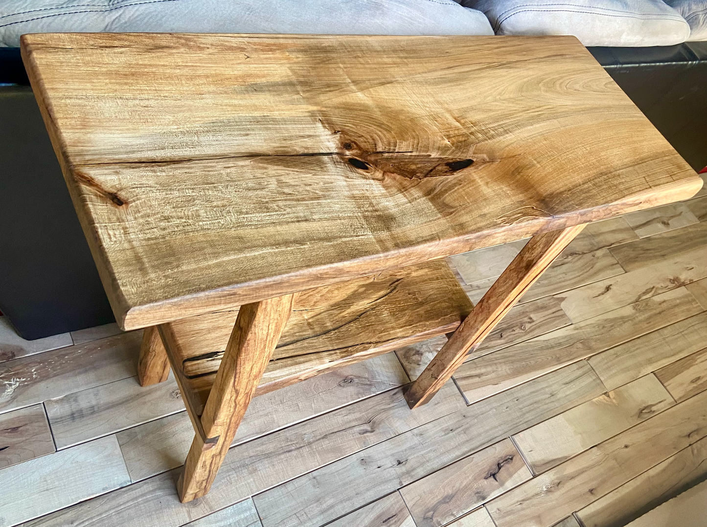 Top-down view of spalted maple sofa or console table, highlighting natural wood grain, warm tones, and wood details. Handcrafted spalted maple console or sofa table styled in a modern living room with a cozy, rustic aesthetic. Detailed view of spalted maple wood grain, showing natural spalting, color variations, and organic patterns. Straight edge entryway table made from spalted maple, featuring unique grain patterns and a smooth, polished surface. Rustic and modern design.