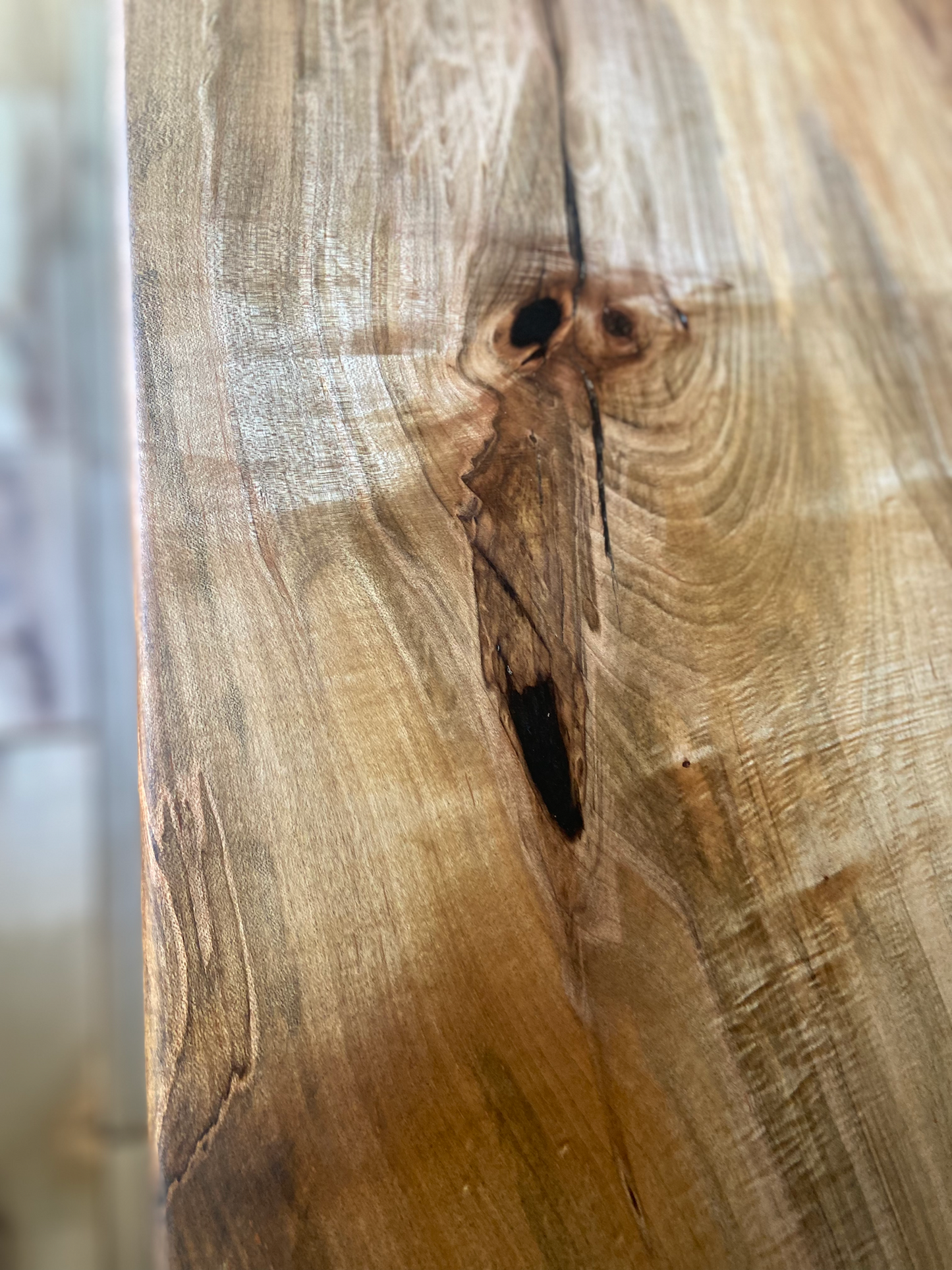 Close up view of spalted maple sofa or console table, highlighting natural wood grain, warm tones, and wood details. Handcrafted spalted maple console / sofa table styled in a modern living room with a cozy, rustic aesthetic. Detailed view of spalted maple wood grain, showing natural spalting, color variations, and organic patterns. Straight edge entryway table made from spalted maple, featuring unique grain patterns and a smooth, polished surface. Rustic and modern design.