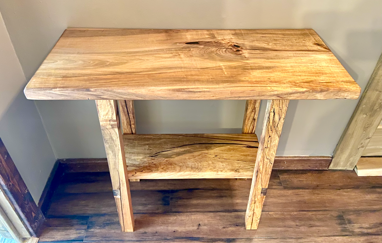 Top-down view of spalted maple sofa or console table, highlighting natural wood grain, warm tones, and wood details. Handcrafted spalted maple console or sofa table styled in a modern living room with a cozy, rustic aesthetic. Detailed view of spalted maple wood grain, showing natural spalting, color variations, and organic patterns. Straight edge entryway table made from spalted maple, featuring unique grain patterns and a smooth, polished surface. Rustic and modern design.