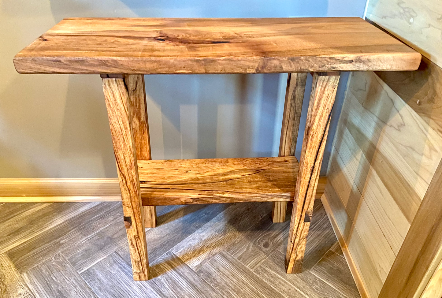 Top-down view of spalted maple sofa or console table, highlighting natural wood grain, warm tones, and wood details. Handcrafted spalted maple console or sofa table styled in a modern living room with a cozy, rustic aesthetic. Detailed view of spalted maple wood grain, showing natural spalting, color variations, and organic patterns. Straight edge entryway table made from spalted maple, featuring unique grain patterns and a smooth, polished surface. Rustic and modern design.