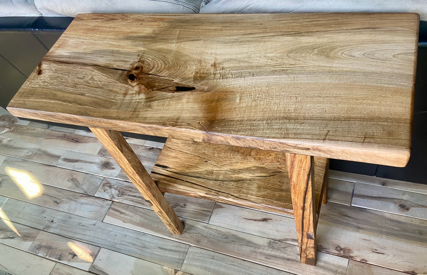 Top-down view of spalted maple sofa or console table, highlighting natural wood grain, warm tones, and wood details. Handcrafted spalted maple console or sofa table styled in a modern living room with a cozy, rustic aesthetic. Detailed view of spalted maple wood grain, showing natural spalting, color variations, and organic patterns. Straight edge entryway table made from spalted maple, featuring unique grain patterns and a smooth, polished surface. Rustic and modern design.
