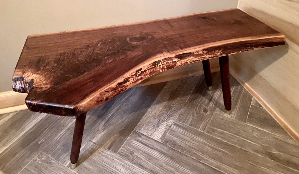 Live edge walnut wood slab coffee table with a natural edge on a wooden floor