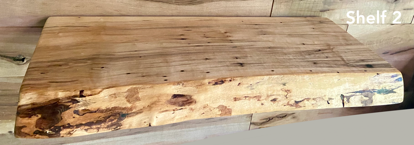 Live edge ambrosia maple floating shelf with live edge and natural grain pattern mounted on wall.