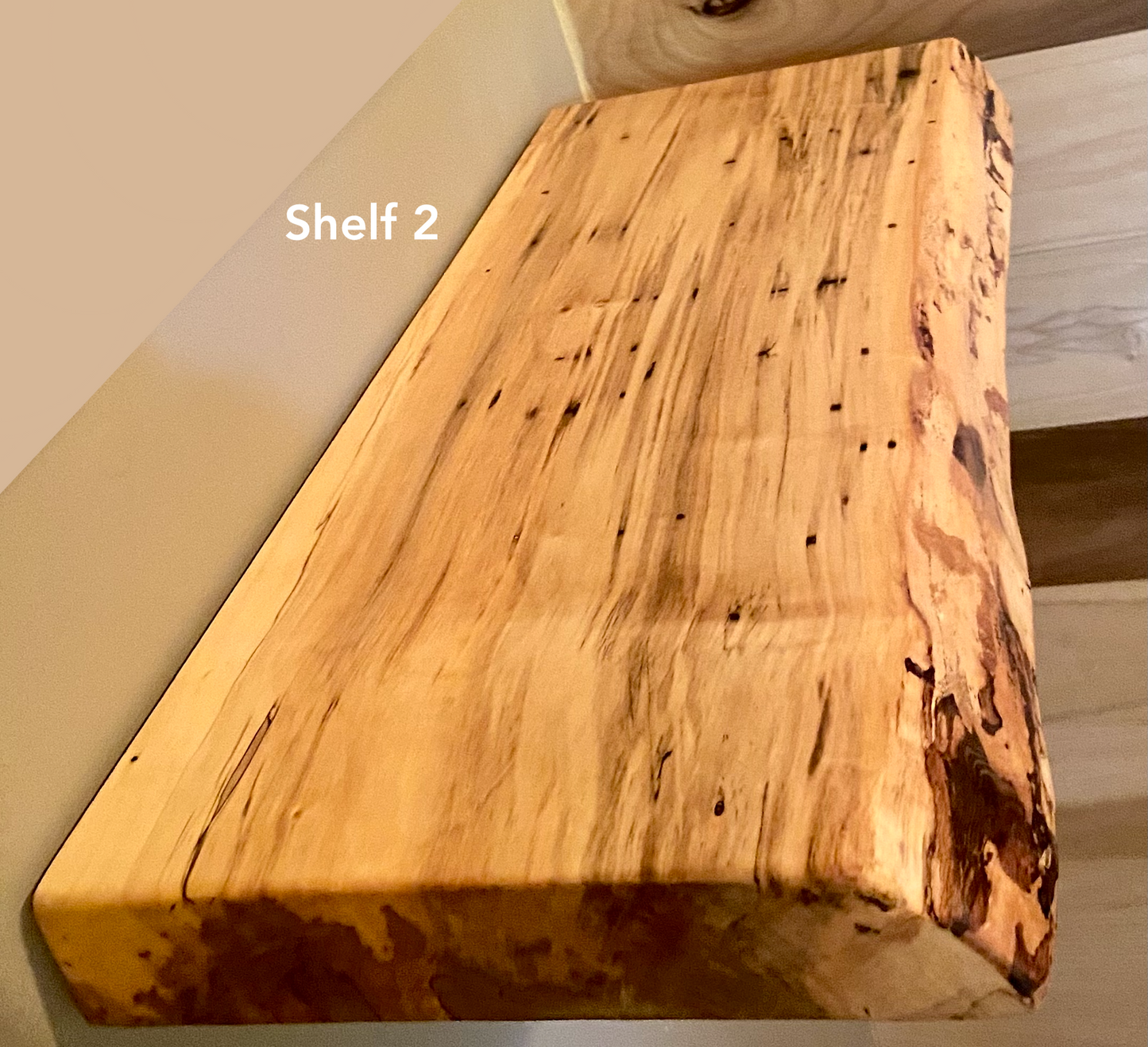 Live edge ambrosia maple floating shelf with live edge and natural grain pattern mounted on wall.