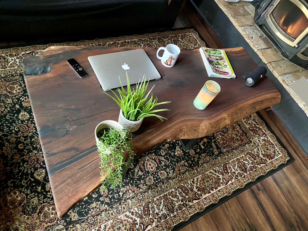 Top-down view of large live edge black walnut coffee table with household items, highlighting natural wood grain, and live edge details. Handcrafted live edge walnut coffee table styled in a modern living room with a cozy, rustic aesthetic. Detailed view of live edge walnut wood grain, showing natural color variations, and organic patterns. Large live edge black walnut coffee table made from walnut featuring unique grain patterns and a smooth, polished surface. Rustic and modern design.