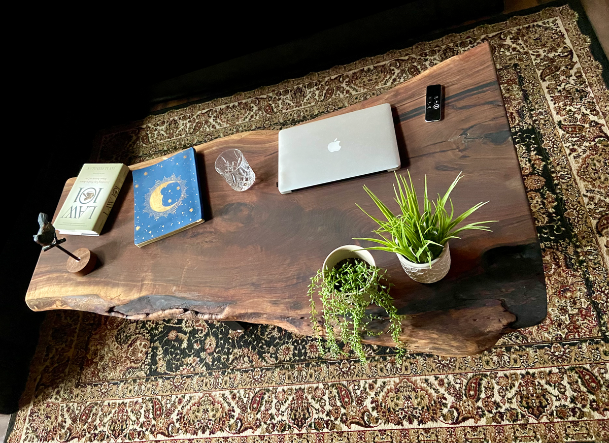 Top-down view of large live edge black walnut coffee table with household items, highlighting natural wood grain, and live edge details. Handcrafted live edge walnut coffee table styled in a modern living room with a cozy, rustic aesthetic. Detailed view of live edge walnut wood grain, showing natural color variations, and organic patterns. Large live edge black walnut coffee table made from walnut featuring unique grain patterns and a smooth, polished surface. Rustic and modern design.