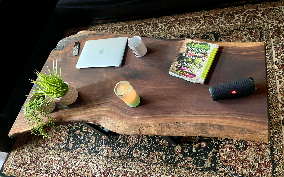 Top-down view of large live edge black walnut coffee table with household items, highlighting natural wood grain, and live edge details. Handcrafted live edge walnut coffee table styled in a modern living room with a cozy, rustic aesthetic. Detailed view of live edge walnut wood grain, showing natural color variations, and organic patterns. Large live edge black walnut coffee table made from walnut featuring unique grain patterns and a smooth, polished surface. Rustic and modern design.