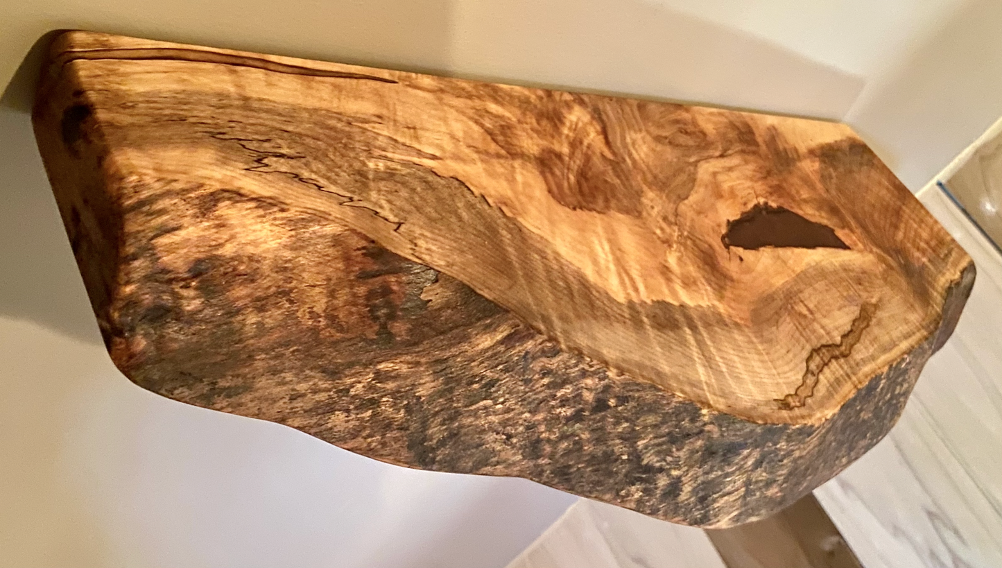 Handcrafted small live edge ambrosia maple floating shelf mounted on a wall. Close-up of the live edge detail on an ambrosia maple floating shelf, highlighting the natural wood grain and unique wormy patterns. Side view of a small ambrosia maple floating shelf with concealed brackets, showcasing its sleek, minimalist design.