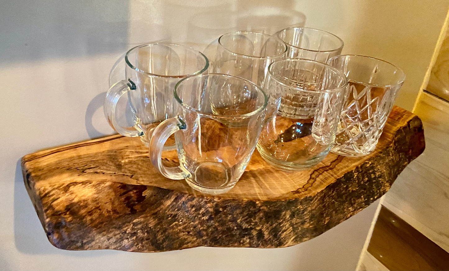 Handcrafted small live edge ambrosia maple floating shelf mounted on a wall, displaying glassware items. Close-up of the live edge detail on an ambrosia maple floating shelf, highlighting the natural wood grain and unique wormy patterns. Side view of a small ambrosia maple floating shelf with concealed brackets, showcasing its sleek, minimalist design.