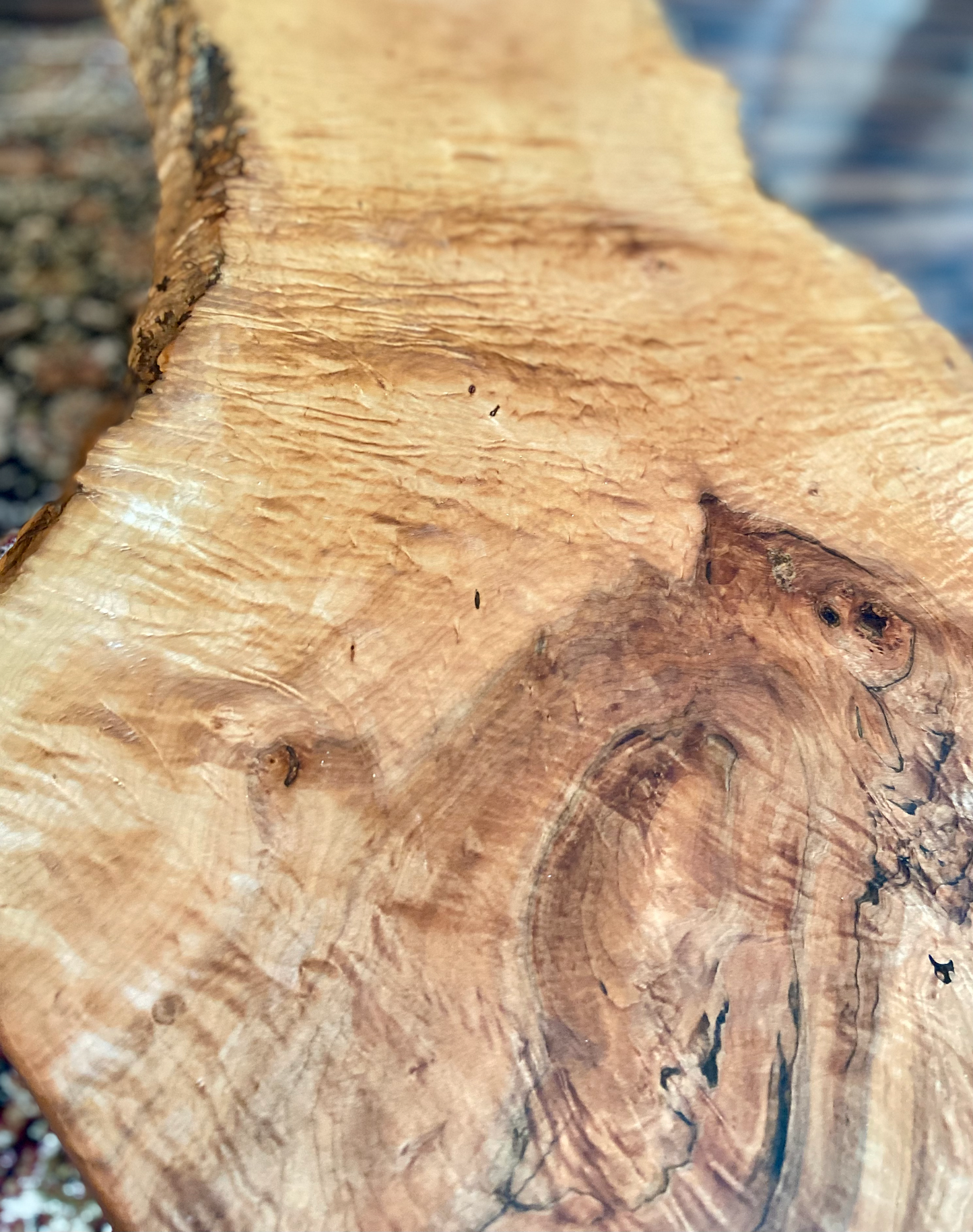 Close-up view of forked live edge maple coffee table with household items, highlighting natural wood grain, and live edge details. Handcrafted maple coffee table styled in a modern living room with a cozy, rustic aesthetic. Detailed view of forked live edge maple wood grain, showing natural spalting, color variations, and organic patterns. Forked live edge coffee table made from spalted maple, featuring unique grain patterns and a smooth, polished surface. Rustic and modern design.