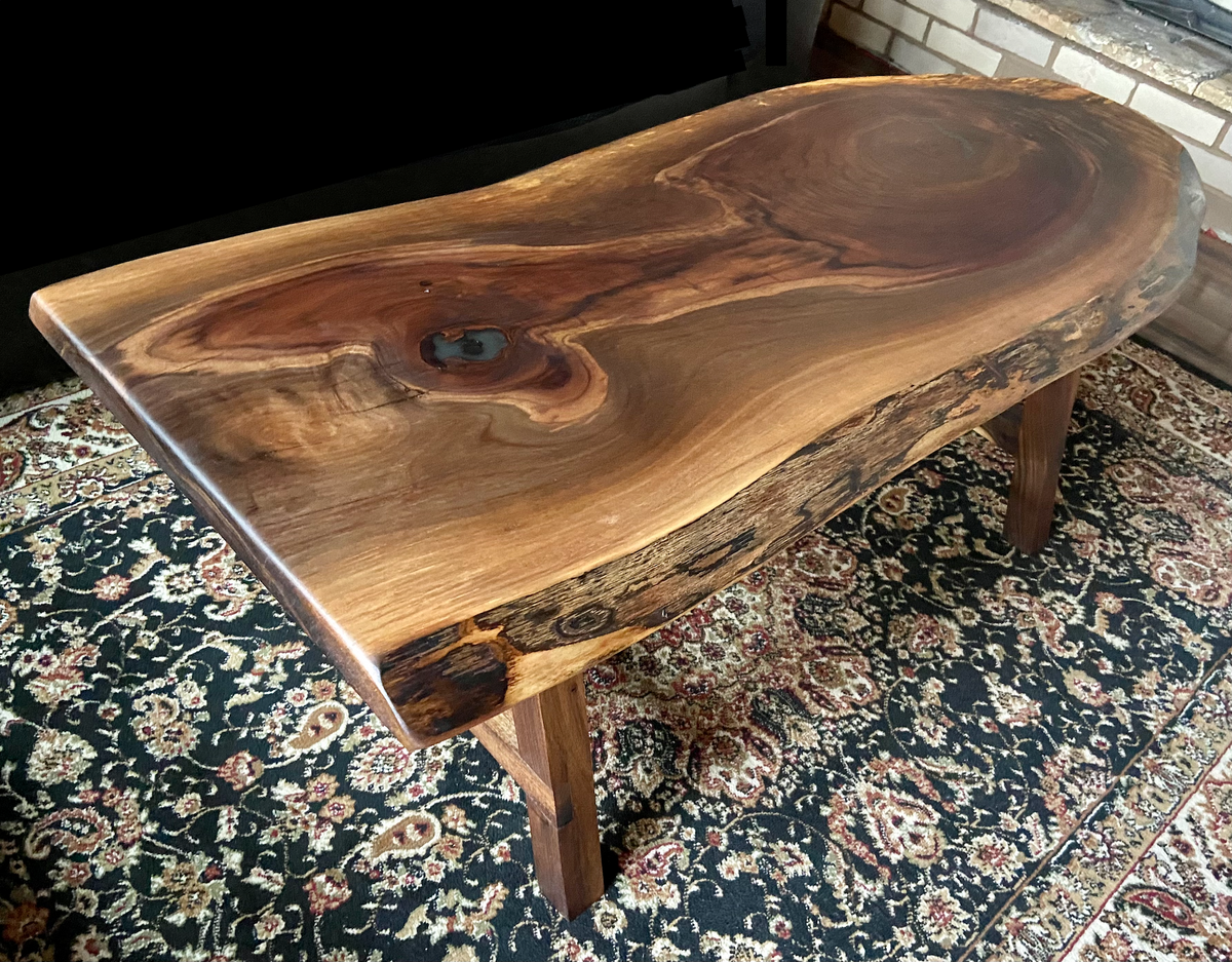 Ultra unique oval rustic natural live edge black walnut coffee table offers natural walnut wood with gorgeous grain patterns, complete with a large knot, a smaller knot, radial grain dancing around the entire table, completed with curl and a long oval shape.