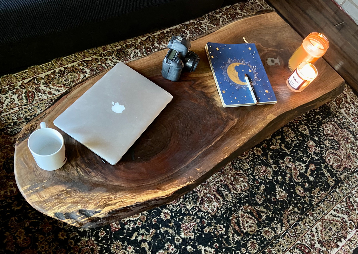 Live edge black walnut wood coffee table with gorgeous grain patterns, complete with a large knot, a smaller knot, and radial grain dancing around the entire table.