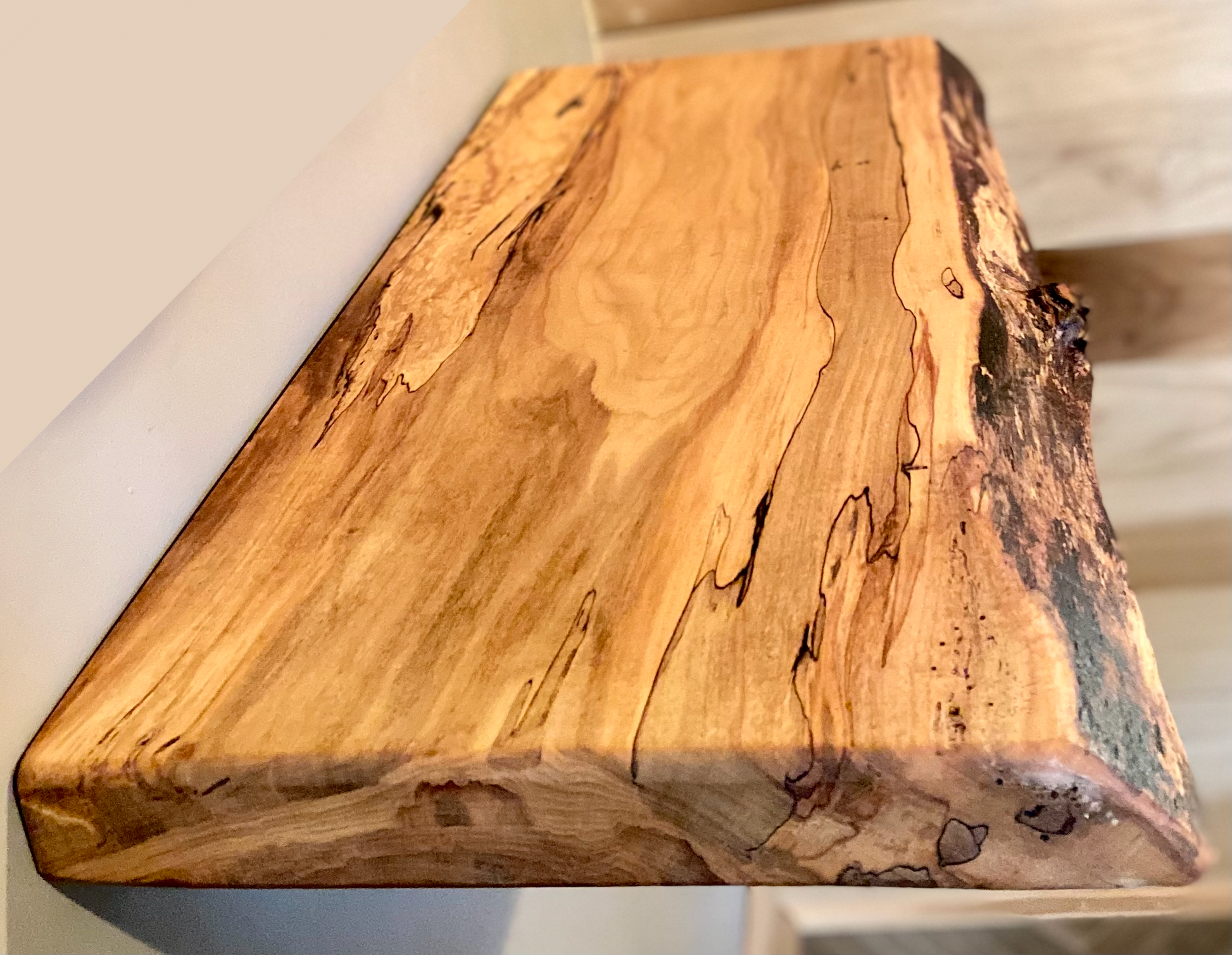 Spalted maple floating shelf with live edge, wall-mounted and handcrafted from natural wood.