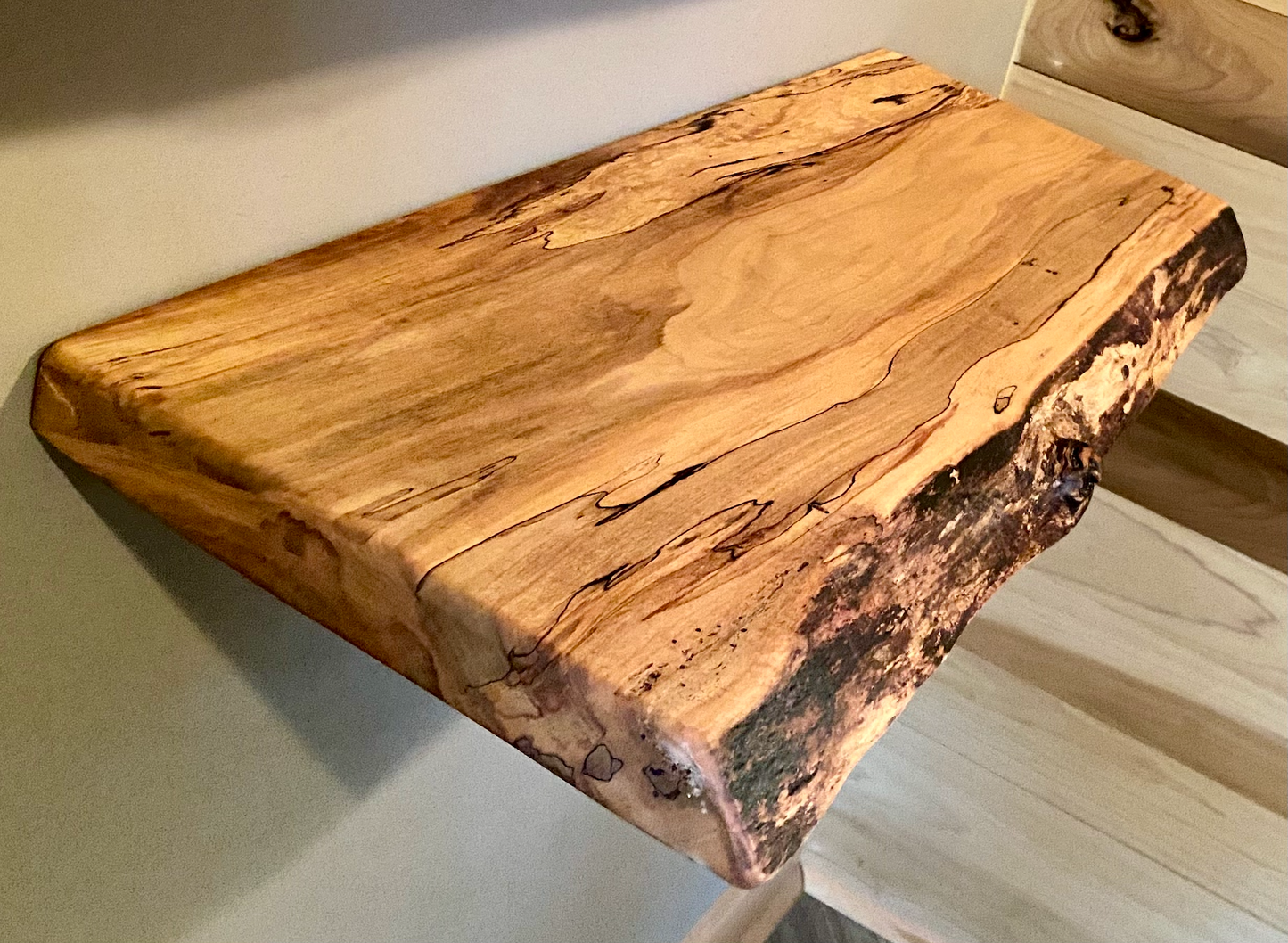 Spalted maple floating shelf with live edge, wall-mounted and handcrafted from natural wood.