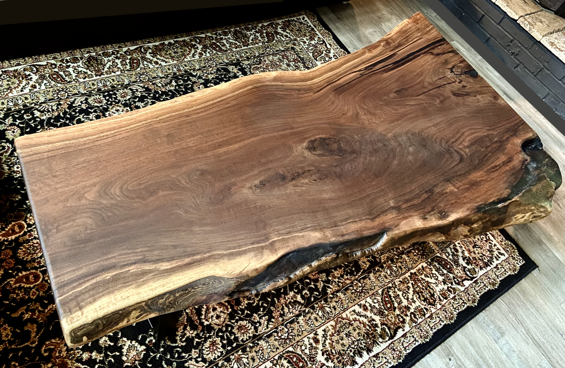 Top-down view of large live edge black walnut coffee table, highlighting natural wood grain, and live edge details. Handcrafted live edge walnut coffee table styled in a modern living room with a cozy, rustic aesthetic. Detailed view of live edge walnut wood grain, showing natural  color variations, and organic patterns. Large live edge black walnut coffee table made from walnut featuring unique grain patterns and a smooth, polished surface. Rustic and modern design.